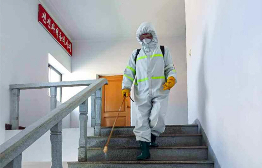 12일 북한이 코로나19 확진 사실을 처음으로 인정한 가운데 전신 보호복을 착용한 북한의 한 방역요원이 시설 소독 작업을 하고 있다.   평양노동신문·뉴스1