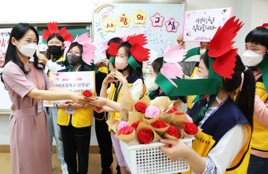 제41회 스승의 날(15일)을 사흘 앞둔 12일 경기 수원시 영통구 산의초에서 학생 대표들이 직접 만든 카네이션과 편지를 선생님에게 전달하며 환하게 웃고 있다. 연합뉴스
