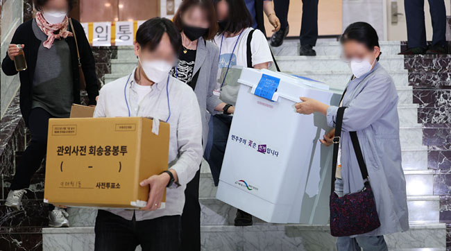 제8회 전국동시지방선거 사전투표 이틀째인 28일 서울 용산구의회에 마련된 사전투표소에서 선거사무 관계자들이 관내 투표함과 관외사전 회송용봉투를 옮기고 있다. 연합뉴스