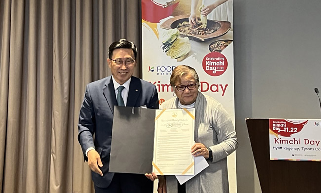 지난 5월 26일 김춘진(왼쪽) 한국농수산식품유통공사(aT) 사장이 아니타 본즈 워싱턴DC 의회 의원으로부터 김치의 날 제정 결의안을 전달받은 뒤 기념촬영을 하고 있다. aT 제공