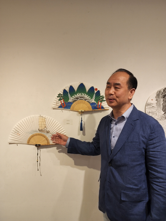 엄재권 한국민화협회 명예회장이 자신의 작품 ‘일월오봉도’와 ‘뱃사공의 항해’에 대해 설명하고 있다.
