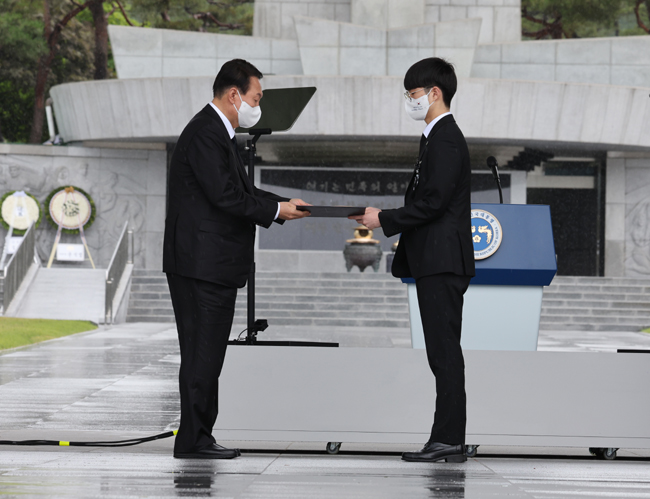 윤석열 대통령이 6일 오전 서울 동작구 국립서울현충원에서 열린 제67회 현충일 추념식에서 지난  4월 8일 대만 해역에서 조난 선박 수색 지원 뒤 복귀하다가 제주 마라도 인근 해상에서 헬기 추락사고로 순직한 고(故) 정두환 경감의 아들 정기훈 군에게 국가유공자 증서를 수여하고 있다. 연합뉴스