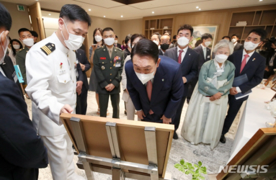 윤석열 대통령이 9일 서울 용산 대통령실 청사에서 천안함 생존 장병과 희생자 유족, 연평해전과 북한 목함지뢰 도발 희생자 유족 등과 오찬에 앞서 순직장병 사진 등을 보며 환담하고 있다. 대통령실사진기자단