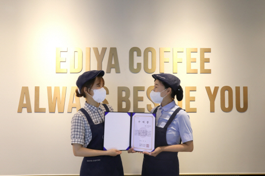 13일 오전 서울 양천구에 있는 이디야커피 목동아델리체점에서 박미경 이디야 점주(오른쪽)와 주현아 메이트가 ‘이디야 메이트 희망기금’ 전달 기념 촬영을 하고 있다. 이디야커피 제공.