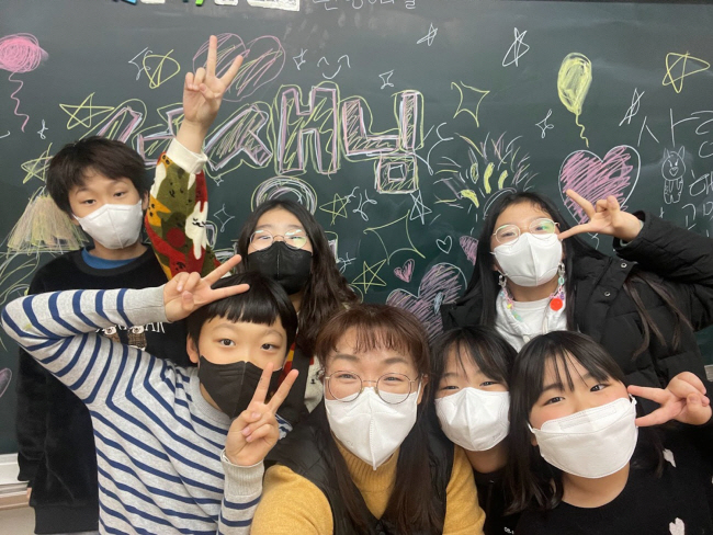 지난 2021년 대구 북구 대구삼영초등학교에서 마지막 학급학력향상수업을 마친 학생들이 성갑영(가운데) 교사에게 그동안 감사했다며 깜짝파티를 열고 기념사진을 찍고 있다.  초록우산어린이재단 제공