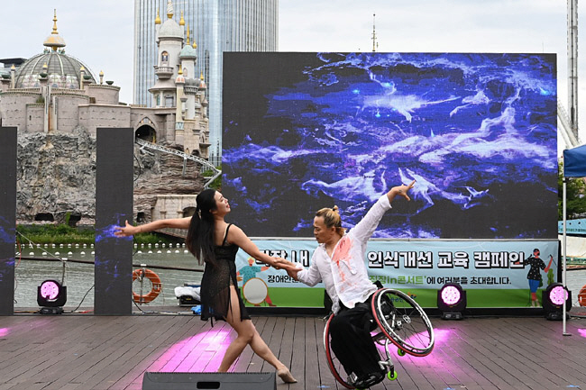 휠체어 댄스스포츠 국가대표 출신인 김남제(오른쪽) 씨가 파트너 김나현 씨와 함께 14일 오후 서울 송파구 석촌호수에서 열린 버스킹에 참가해 음악에 맞춰 춤을 추고 있다.   한국장애인고용공단 제공