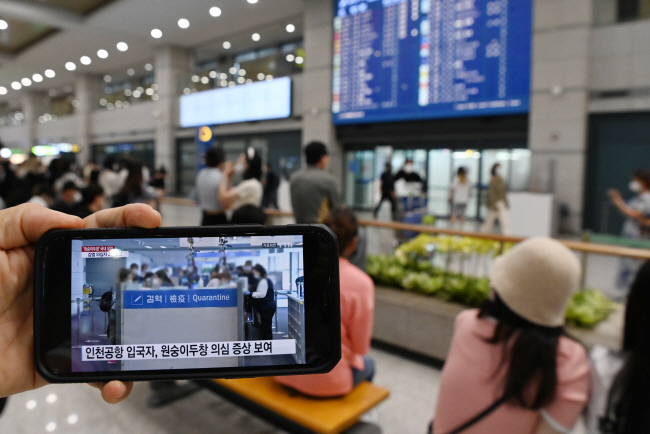 원숭이두창 감염 의심환자 2명의 국내 유입으로 출입국 방역에 대한 경각심이 커지고 있는 가운데 22일 오전 인천국제공항 입국장에서 한 시민이 스마트폰으로 관련 보도 내용을 시청하고 있다. 김동훈 기자