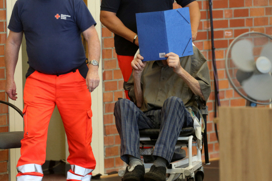 나치 정권에 부역한 혐의로 기소된 요제프 쉬츠가 28일 독일 브란덴부르크 체육관에 마련된 임시 법정에 얼굴을 가린 채 휠체어를 타고 입장하고 있다. 올해 101세인 쉬츠는 나치 전쟁범죄 혐의로 독일 법정에 선 피고인 가운데 최고령으로 기록됐다. AFP연합뉴스