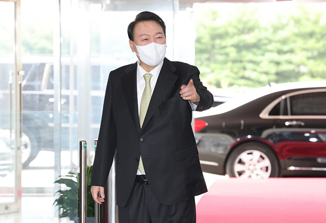 윤석열 대통령이 12일 오전 서울 용산 대통령실 청사로 출근하면서 전일 기자실 코로나19 확산에 따른 도어스테핑(약식회견) 잠정 중단 방침에도 불구하고 취재진이 손을 흔들며 질문을 던지자 기자를 가리키면서 답변을 하고 있다. 연합뉴스