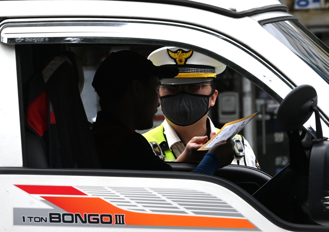 ‘횡단보도 앞 일시 정지’ 의무를 확대하는 내용의 도로교통법 개정안이 전면 시행된 12일 오전 서울 종로구 이화사거리에서 경찰관이 한 운전자에게 우회전 방법이 적힌 안내문을 주며 계도 활동을 하고 있다. 김호웅 기자