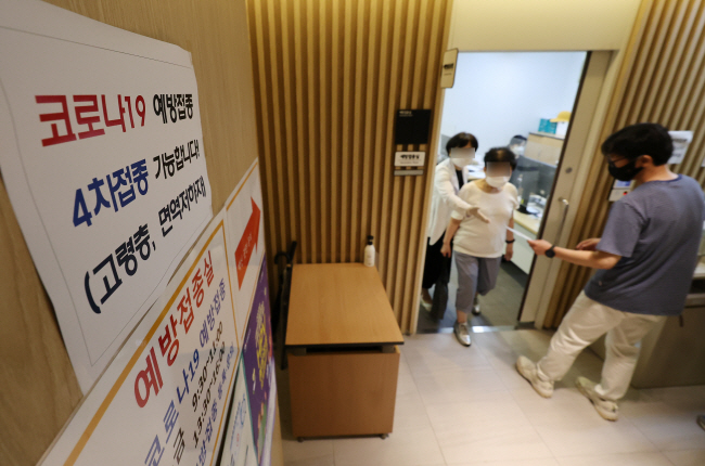 코로나19 백신 4차 접종 대상자를 50대와 18세 이상 기저질환자로 확대하기로 한 13일 서울의 한 보건소 건강센터에서 보건소 직원이 백신 4차 접종을 받는 어르신을 안내하고 있다. 연합뉴스