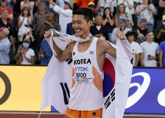 남자높이 뛰기 우상혁 선수가 18일(현지시간) 미국 오리건주 유진의 헤이워드필드에서 열리고 있는 2022 세계육상선수권대회에서 은메달을 수상하고 태극기를 두르는 세러머니를 하고 있다. AP·연합뉴스