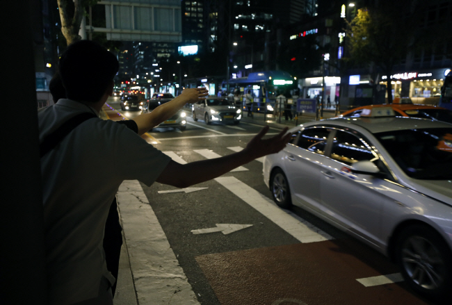 지난 19일 밤 서울 도심 거리에서 시민들이 택시를 잡으려고 손을 흔들고 있다. 택시기사들이 택배·배달 등 타 업종으로 옮겨가며 심야운행 택시 수가 줄어 연일 귀가전쟁이 벌어지고 있다.  뉴시스
