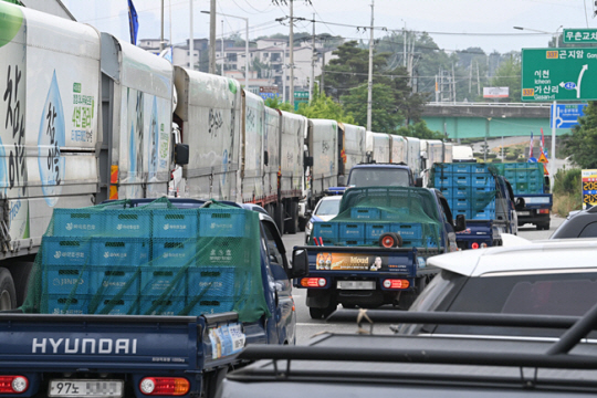 지난 6월 9일 경기 이천시 부발읍 하이트진로 이천공장 앞에서 파업 중인 전국민주노동조합총연맹 공공운수노조 화물연대(화물연대) 노조원들이 농성중인 가운데, 멈춰선 파업 차량들 옆으로 주류도매업체 차량이 소주를 싣고 나오고 있다. 문화일보 자료 사진