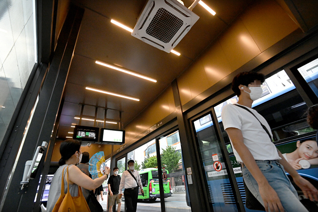 5일 오전 서울 마포구 홍대입구역에 설치된 ‘스마트 셸터’에서 한 시민이 더위를 못 참고 부채질을 하고 있다. 스마트 셸터는 스크린 도어를 연 채 에어컨이 가동되고 있어 냉방 효과는 없다.   신창섭 기자