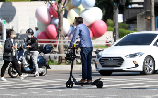 서울의 한 도심 거리에서 한 시민이 헬멧을 쓰지 않은 채 전동킥보드를 타고 이동하고 있다. 뉴시스 자료사진