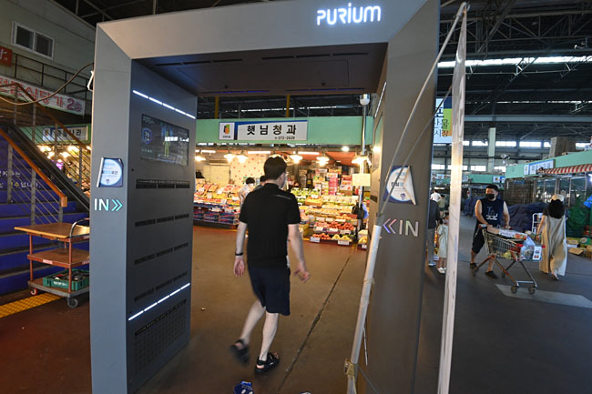 코로나19 신규 확진자가 15만 명에 육박해 118일 만에 최다치를 기록한 9일 오전 서울 마포구 농수산물시장 출입구에서 한 시민이 대형 에어 샤워와 전신 소독기를 통과해 매장에 들어가고 있다.  김동훈 기자