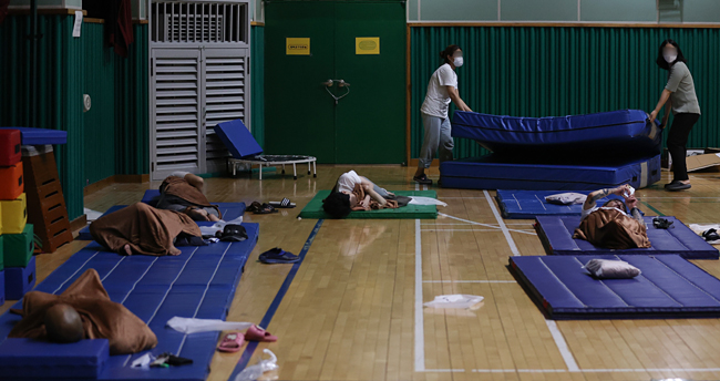 9일 서울 동작구청 관계자들이 문창초등학교에 마련된 임시주거시설을 찾는 침수피해 주민들이 늘자 매트를 추가로 꺼내고 있다. 연합뉴스