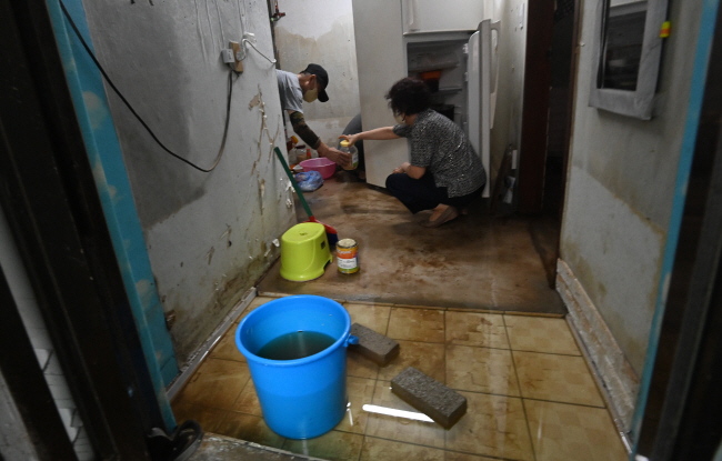 11일 오전 서울 관악구 신사동의 한 반지하 주택에서 집중호우로 인해 침수 피해를 당한 주민이 집기류를 정리하고 있다.  신창섭 기자