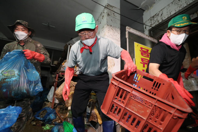 주호영(가운데) 국민의힘 비상대책위원장과 권성동(맨 오른쪽) 원내대표가 11일 오전 폭우 피해를 입은 서울 동작구 사당동의 한 빌딩 지하에서 수해 복구 자원봉사를 하고 있다.   국회사진기자단