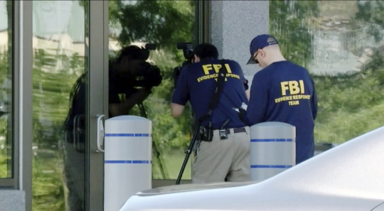 미국 오하이오주 신시내티의 연방수사국(FBI) 지부 건물에서 11일(현지시간) 무장괴한의 침입사건이 발생한 가운데 FBI 직원들이 사건 현장에서 증거 조사 등을 벌이고 있다. AP·연합뉴스