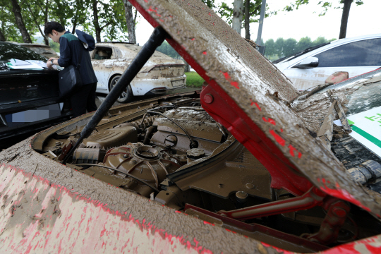 중부지방 집중호우로 발생한 차량 피해 추정손해액이 1400억원을 돌파한 가운데 14일 오전 경기 과천시 서울대공원 주차장에 견인된 한 침수차량의 엔진룸 내부까지 진흙으로 덮여 있다. 뉴시스