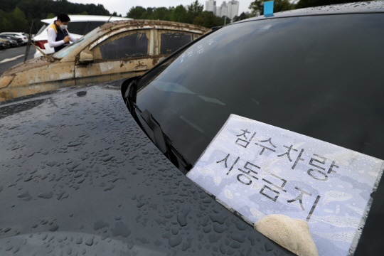 중부지방 집중호우로 발생한 차량 피해 추정손해액이 1400억원을 돌파한 가운데 14일 오전 경기 과천시 서울대공원 주차장에 견인돼 온 한 침수차량 앞 유리에 ‘시동금지’ 표지판이 붙어 있다. 뉴시스