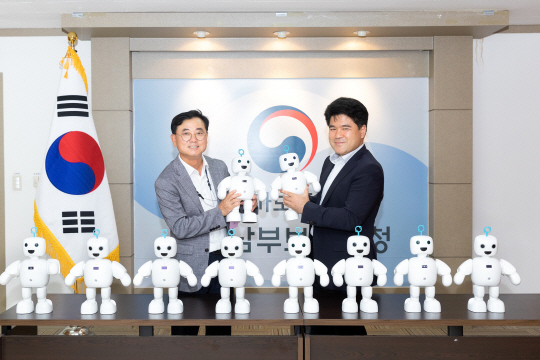 최형식(왼쪽) 효성 커뮤니케이션실 상무와 강병구 서울남부보훈지청장이 18일 국가유공자 건강지원로봇 전달식에서 효성이 기증한 반려로봇 ‘파이보’를 들어보이고 있다. 효성 제공