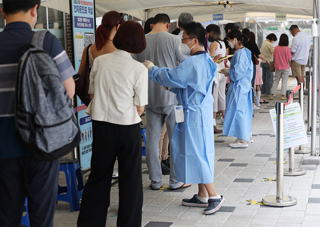 26일 오전 서울 마포구보건소에 마련된 선별진료소에서 시민과 외국인들이 검사를 받기 위해 줄을 서고 있다. 연합뉴스