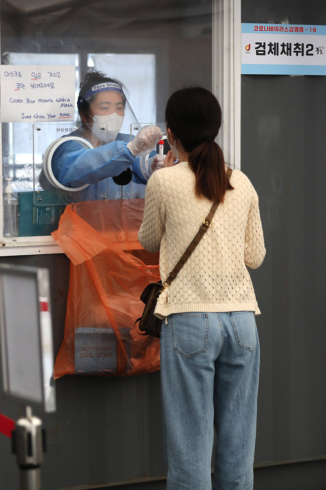 26일 오후 서울 중구 서울역광장에 마련된 코로나19 임시 선별검사소에서 의료진이 검체를 채취하고 있다. 뉴시스