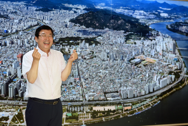 김경호 광진구청장이 구청 1층 벽에 붙어 있는 광진구 전경 사진 앞에서 환하게 웃어 보이고 있다. 도시행정전문가인 김 구청장은 광진의 도시계획을 전면 재정비하기 위해 ‘2040 광진플랜’을 준비하고 있다. 윤성호 기자