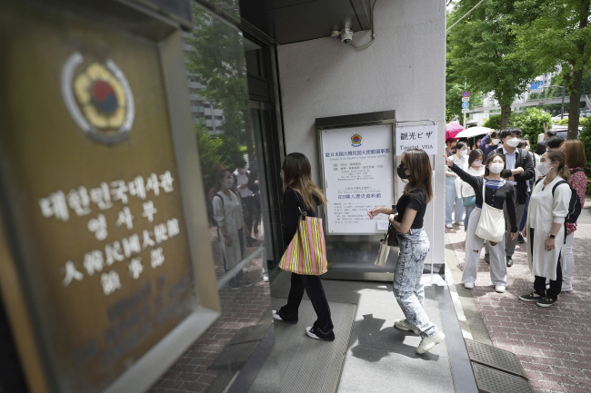 한국이 코로나19 팬데믹에 따라 중단했던 관광비자 발급을 재개한 지난 6월 1일 일본 도쿄의 한국 영사관 앞에 비자 발급을 신청하는 줄이 길게 서 있다. 한국은 오는 3일 0시부터는 해외 입국자의 입국 전 코로나19 유전자증폭(PCR) 검사 의무화도 폐지한다.  AP뉴시스