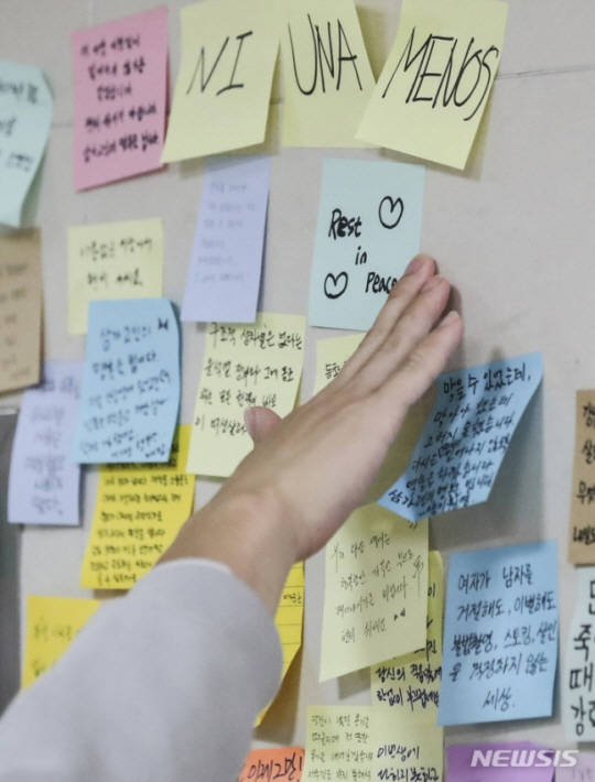 지난 14일 서울교통공사 역무원 스토킹 살인사건이 발생한 서울 지하철 2호선 신당역 여자화장실 앞에 마련된 추모공간에서 18일 한 시민이 포스트잇을 붙이며 추모하고 있다.                                                                                                  뉴시스