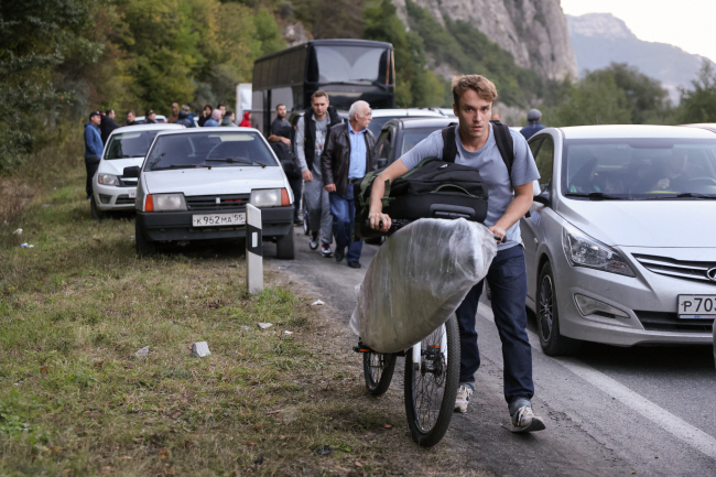 러시아가 우크라이나 전쟁 투입을 위해 예비군 30만 명 동원령을 내린 가운데 26일 징집을 피하려는 러시아 남성들이 차량과 자전거를 이용해 조지아와의 국경지대인 베르흐니 라르스 검문소로 향하고 있는 모습. 이에 러시아는 탈주를 막기 위해 국경 폐쇄를 검토하고 있다.  EPA TASS 연합뉴스