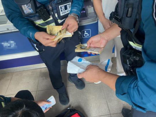 부산 남부경찰서 광민지구대 경찰관들이 보이스피싱 현금 수거책이 송금하지 못한 현금을 회수하고 있다. 부산경찰청 제공