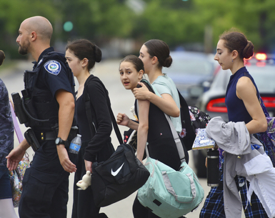 지난 7월 4일(현지시간) 미국 일리노이주 시카고 인근 하이랜드파크에서 독립기념일 퍼레이드 도중 총격 사건이 발생한 후 학생들이 경찰의 호위를 받으며 길을 건너고 있다. AP연합뉴스