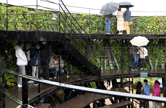10일 서울 마포구 하늘공원을 찾은 시민들이 갑작스런 소나기에 구조물 밑에서 비를 피하고 있다.