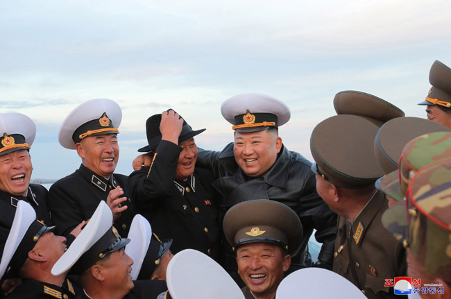김정은 북한 국무위원장이 연포온실농장 준공식에서 김명식(뒷줄 왼쪽 세 번째) 해군사령관과 모자를 바꿔 쓰고 사진을 찍고 있다. 11일 조선중앙통신은 “김 위원장이 노동당 창건일인 10일 함남 함주군 연포지구의 대규모 남새(채소)생산기지인 연포온실농장 준공식에 참석해 몸소 준공 테이프를 끊었다”고 보도했다. 연합뉴스