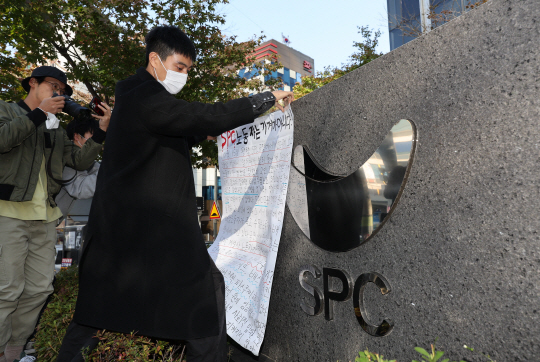 지난 20일 오후 서울 양재동 SPC 본사 앞에서 열린 평택 SPC 계열사 SPL의 제빵공장 사망 사고 희생자 서울 추모행사에서 성공회대 노학연대모임 가시 관계자가 대자보를 붙이고 있다. 연합뉴스