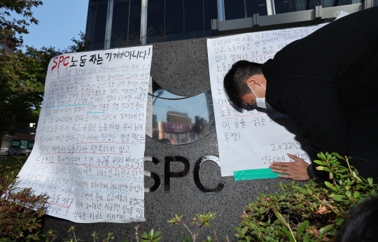지난 20일 서울 서초구 양재동 SPC 본사 앞에서 열린 평택 SPC 계열사 SPL의 제빵공장 사망 사고 희생자 서울 추모행사에서 성공회대 노학연대모임 가시 관계자가 대자보를 붙이고 있다. 연합뉴스