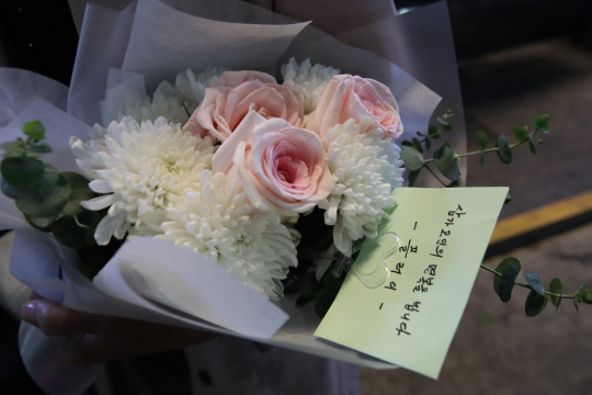 30일 오후 서울 용산구 이태원 압사 참사 현장 인근에 마련된 추모공간에서 한 시민이 헌화할 꽃을 들고 추모하기 위해 대기하고 있다. 뉴시스