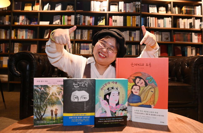 지난 11일 여의도 카페꼼마에서 만난 이연실 이야기장수 대표가 올해 발간한 책들을 가리키며 웃고 있다. ‘가장 좋은 것을 너에게 줄게’(왼쪽부터), ‘전쟁일기’ ‘가녀장의 시대’ ‘은혜씨의 포옹’. 김동훈 기자