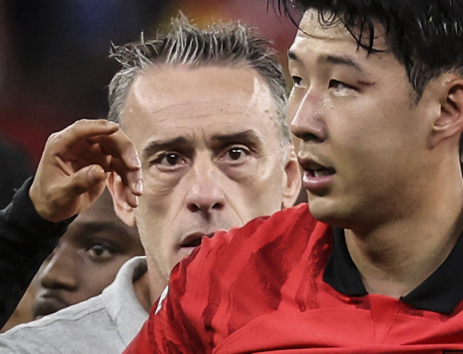 손흥민(오른쪽)이 28일 밤(한국시간) 카타르 알라이얀의 에듀케이션 시티 스타디움에서 열린 2022 카타르월드컵 H조 조별리그 2차전에서 패한 후 눈시울을 붉히고 있다. 뒤에 서 있는 파울루 벤투 감독의 눈도 충혈된 것 같다. 뉴시스