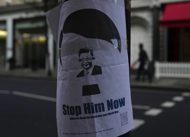 영국 런던의 중국대사관 앞에 세워진 기둥에 28일 독일 나치 지도자 아돌프 히틀러를 형상화한 시진핑 중국 국가주석 사진과 함께 ‘이제 그를 멈추게 하자’는 문구가 적힌 전단이 붙어 있다. 런던에서는 중국의 ‘백지혁명’을 지지하는 동조 시위도 이날 이어졌다. AP 뉴시스