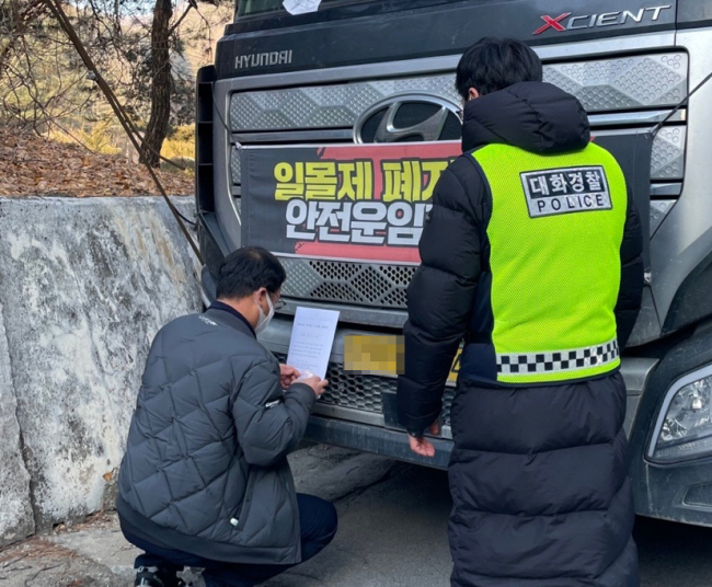2일 오전 강원 영월군 한반도면 한일현대시멘트 앞에서 국토교통부와 영월군청 관계자들이 경찰의 엄호 속에 화물연대 조합원 차량에 업무개시명령서를 붙이고 있다. 연합뉴스