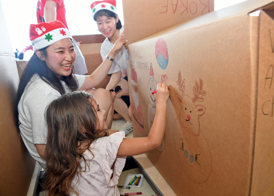 지난 3일 미국 괌 앤더슨 공군기지에서 크리스마스 공수작전에 참가하는 공군 제15특수임무비행단 소속 장병들이 산타모자를 쓰고 마이크로네시아(Micronesia) 지역 섬에 공수할 화물 상자를 지역 주민들과 장식하고 있다. 공군 제공