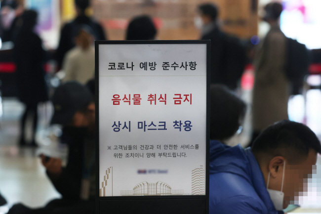 정부가 실내 마스크 의무화 해제 여부를 이달 말까지 결정하겠다고 밝힌 가운데 7일 오전 서울의 한 컨벤션센터에서 한 남성이 마스크를 턱으로 내린 채 ‘상시 마스크 착용’ 안내문 뒤에 앉아 있다.  연합뉴스