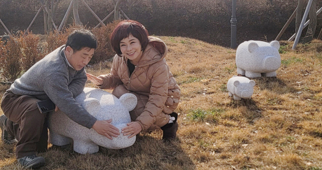 현숙(오른쪽) 가수와 한진섭 조각가가 돌조각 돼지의 코를 만지며 복을 빌고 있다.   김제시 제공