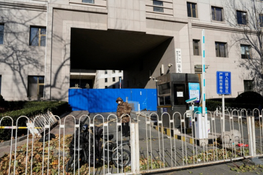 지난 10일(한국시간) 코로나19 확산으로 폐쇄된 중국 베이징의 한 병원의 입구에서 병원 노동자가 낙엽을 쓸고 있다. AP뉴시스