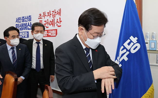 이재명(오른쪽) 더불어민주당 이재명 대표가 15일 오후 국회 대표실에서 김진표 국회의장이 여야에 제안한 내년도 예산안 중재안을 전격적으로 수용하기로 했다는 내용의 기자회견을 한 뒤 대표실을 나서며 시계를 보고 있다. 연합뉴스